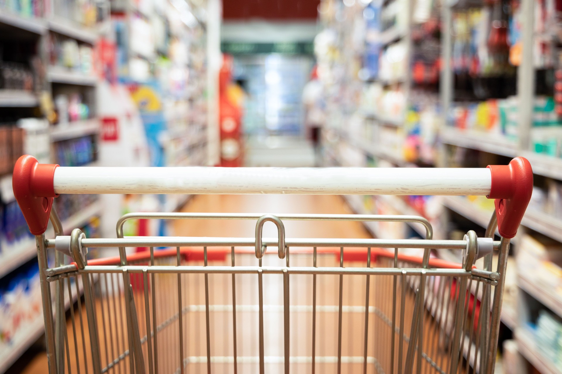 Perspective view shopping trolley cart with supermarket aisle blurred background